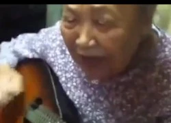 Cụ bà ôm đàn guitar hát một cách hào hùng