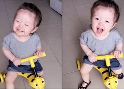 Bé Cadie Mộc Trà cười tít mắt trên xe ba bánh