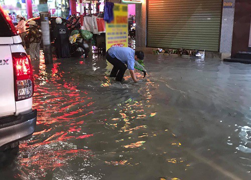 Giữa trời mưa, người đàn ông nhặt bao nilon, khơi nắp cống bị tắc