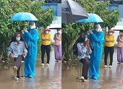 Nữ tình nguyện viên ở TP.HCM cầm ô che cho cụ già dưới trời mưa lớn