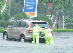 Cảnh sát dầm mưa giúp người dân đẩy xe qua đoạn đường ngập nước