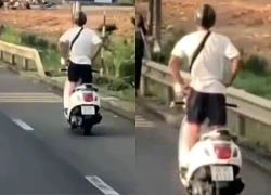 Nam tài xế buông 2 tay, đứng trên xe máy đang chạy trên quốc lộ